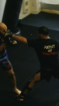Person practicing martial arts with another individual in a dark room.