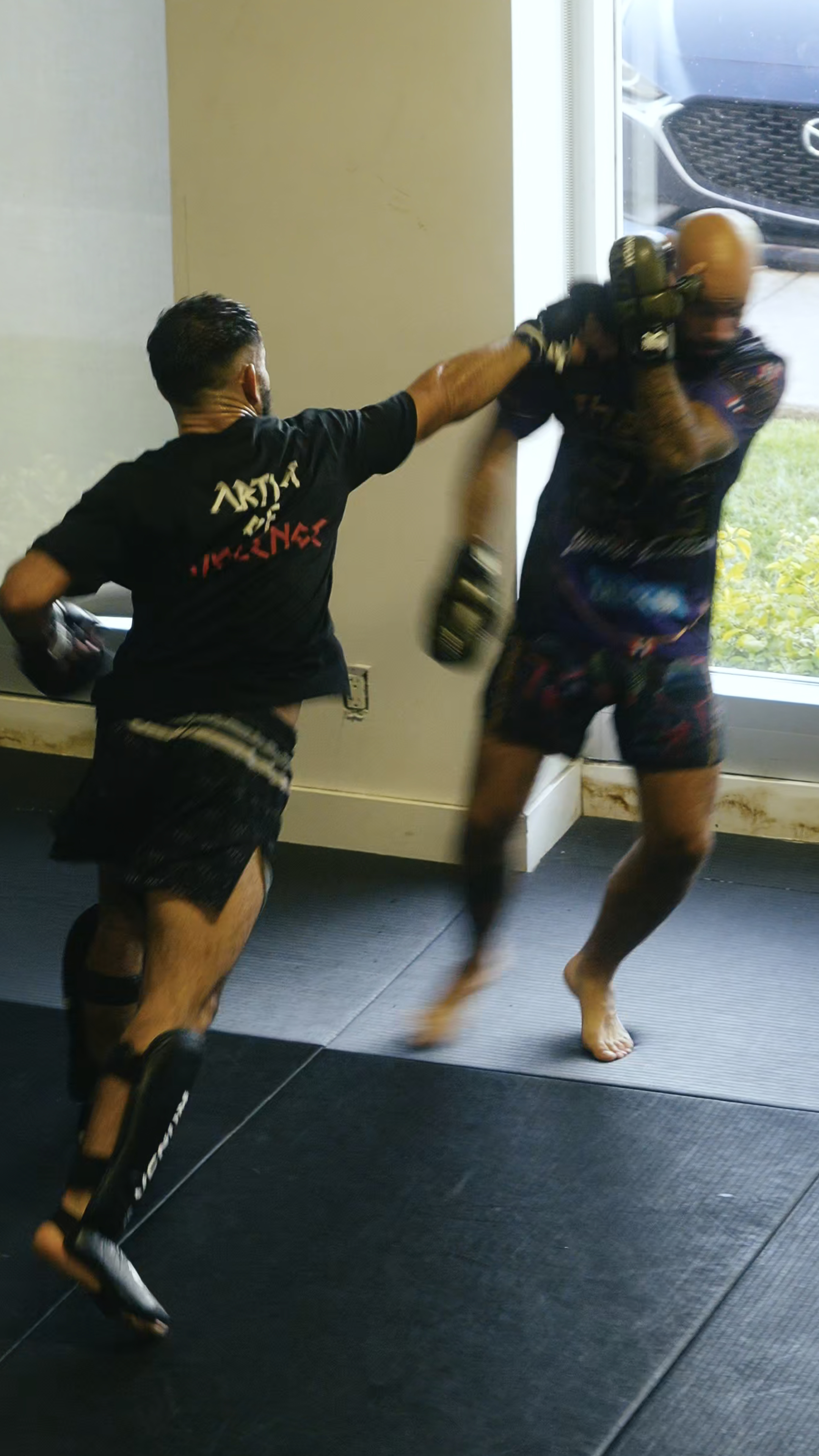 Two individuals practicing martial arts in a room with a window.